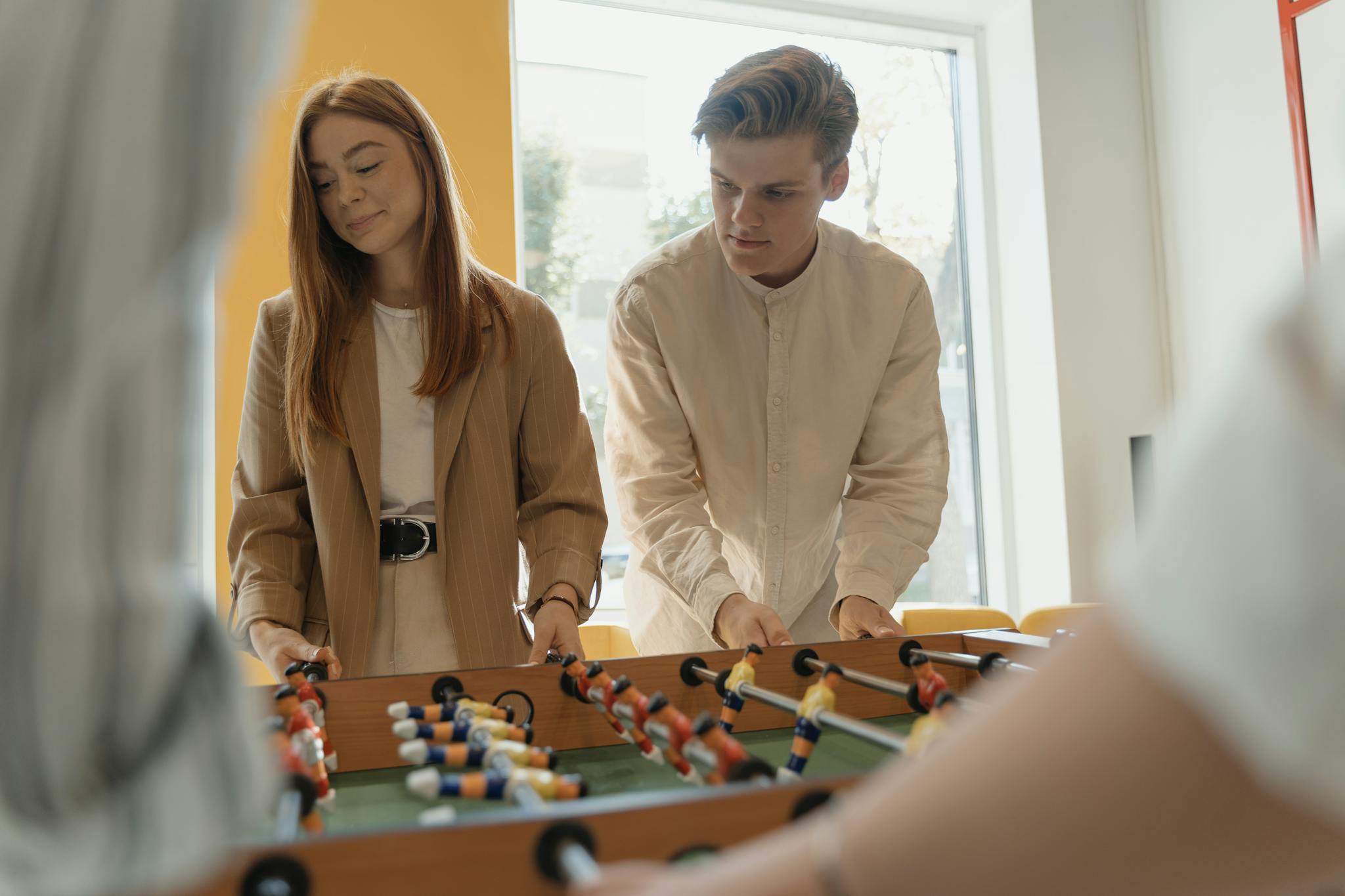 Two young women having fun playing foosball indoors, captured in a lively moment.